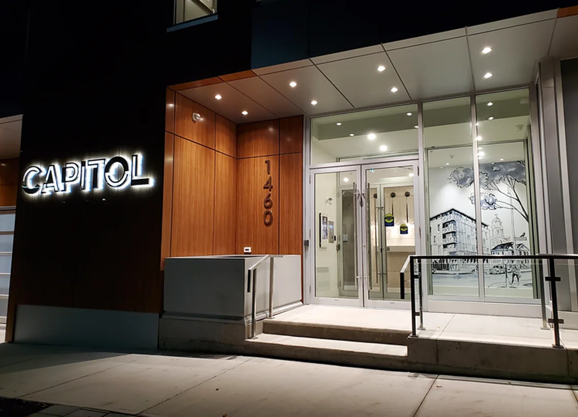 Capitol Suites entrance at night with halo-lit dimensional letters on a wood façade