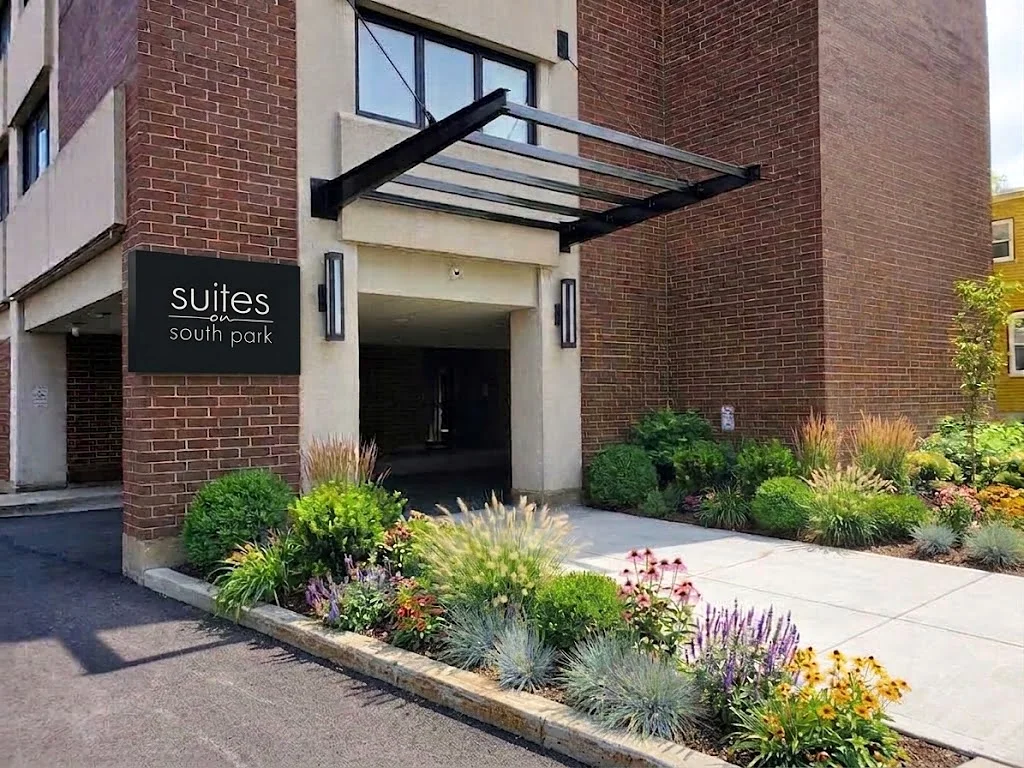 Suites on South Park entrance in Halifax, with a dark panel sign on the brick façade and landscaped garden beds